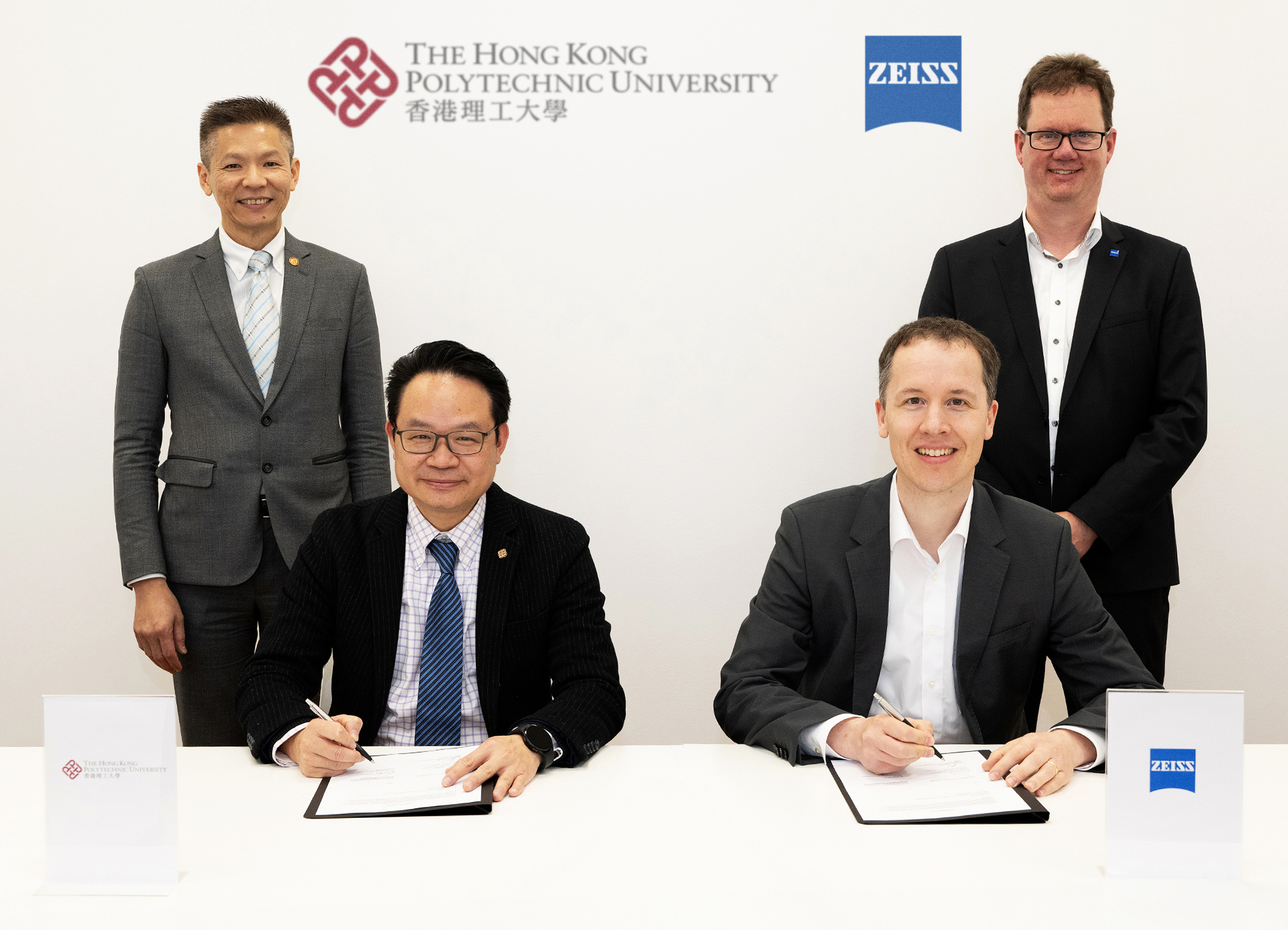 Witnessed by Prof. Chea-su Kee, Head of the PolyU School of Optometry (back row, left) and Mr Timo Kratzer, Head of Lens Product Development at ZEISS Vision Care (back row, right), Mr Kelvin Wong, Director of Knowledge Transfer and Entrepreneurship of PolyU (front row, left) and Dr Benjamin Viering, Chief Technology Officer and Chief Operating Officer of ZEISS Vision Care (front row, right) signed the licensing agreement.